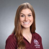 A person smiling, wearing a maroon polo shirt.
