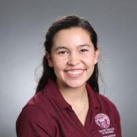 A person smiling in a maroon shirt.