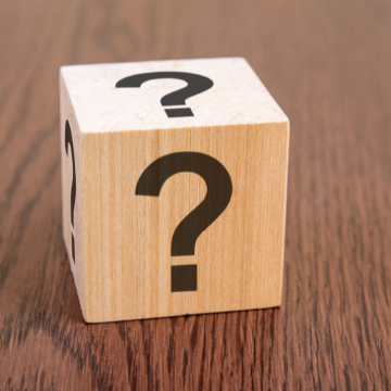 Photo of a wooden block with question marks on all sides