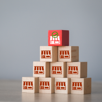 Photo of stacked building blocks with graphic images of a storefront on each one.