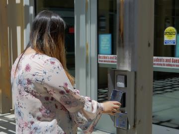 Person using an access card to open a glass door.