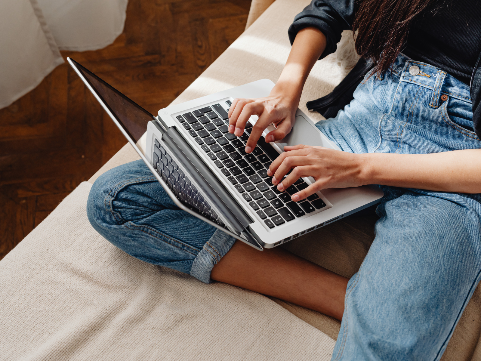 Woman uses her computer while sitting on her bed