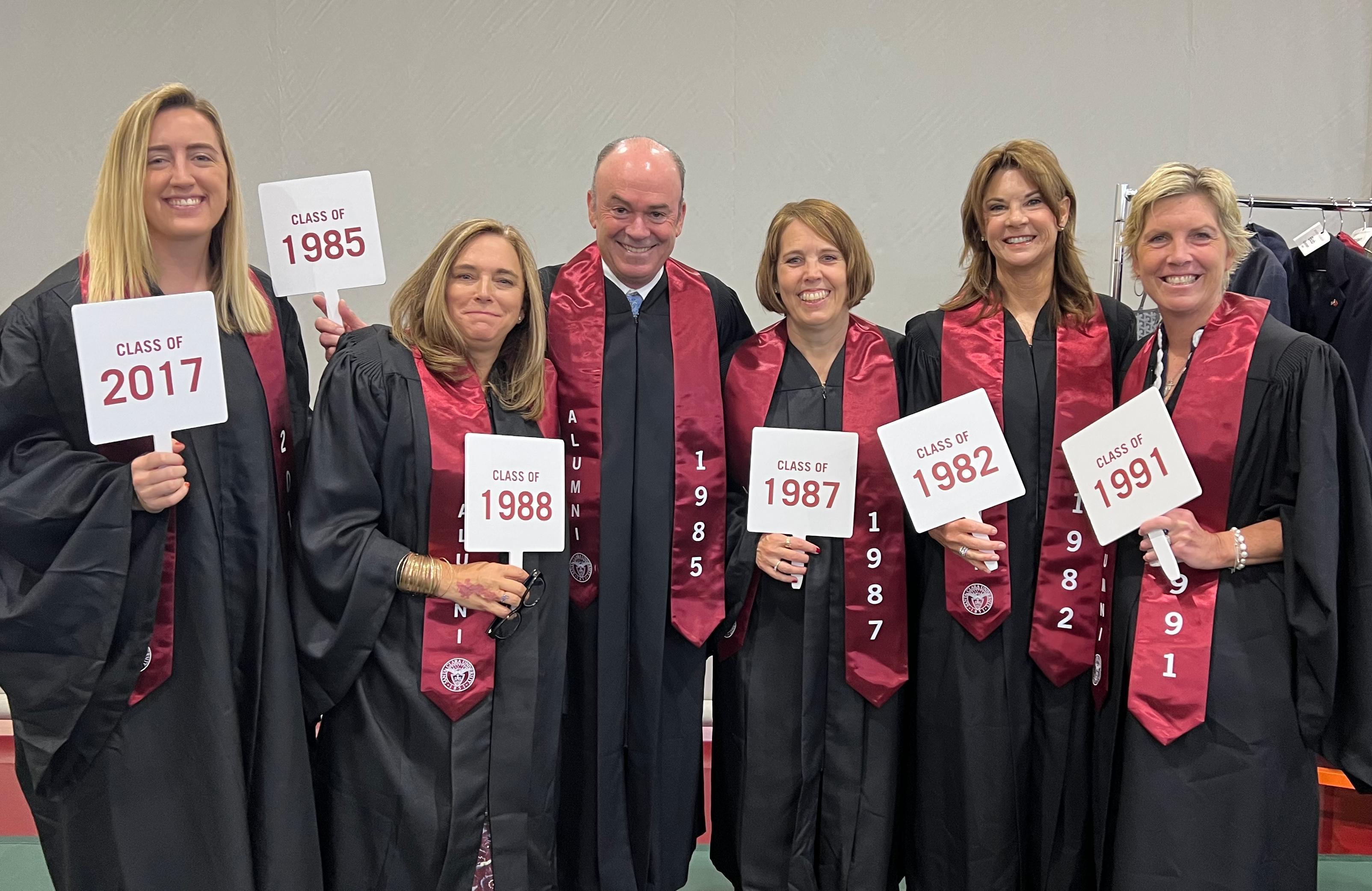 Group of people in graduation robes holding certificates and smiling.