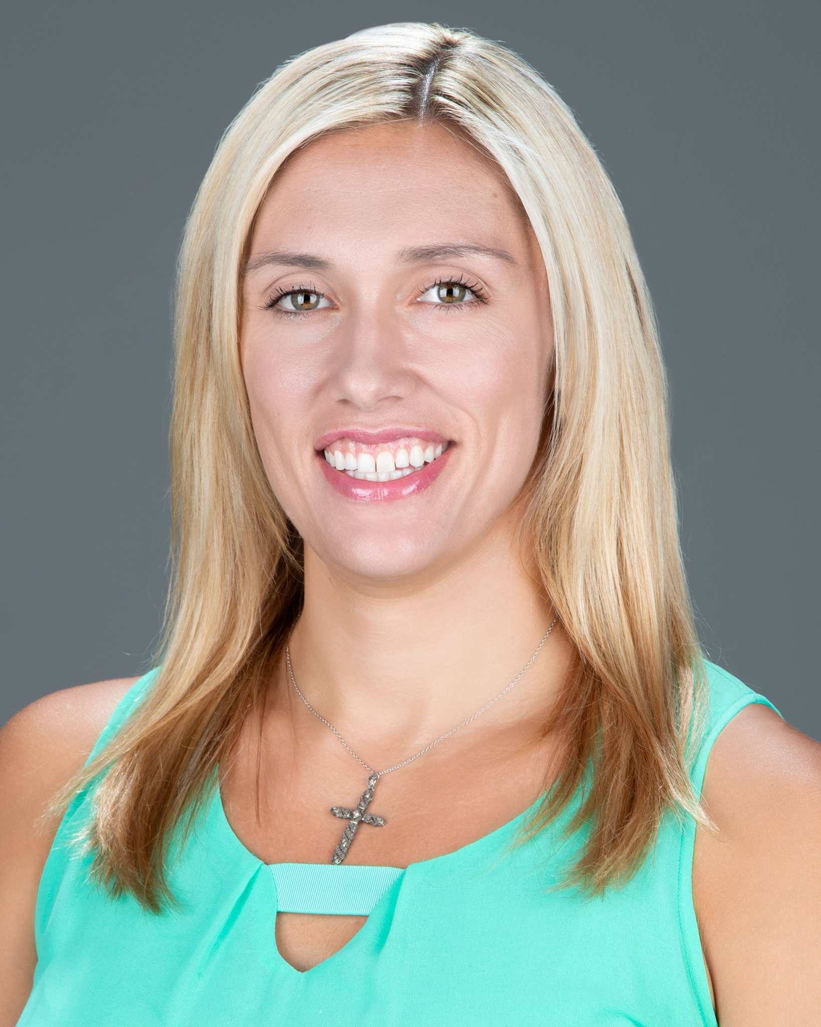 A person smiling with a gray background, wearing a light green top.