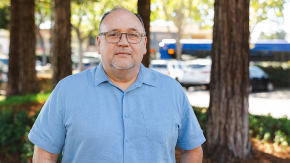 An older man in glasses and blue, collared shirt.