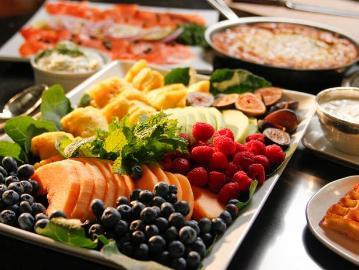 Alt text: A platter of assorted fruits including blueberries, strawberries, raspberries, pineapple, and greens.