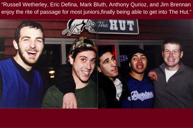 Five people smiling in front of a sign reading 