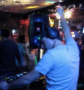 A DJ performing in a dimly lit nightclub.