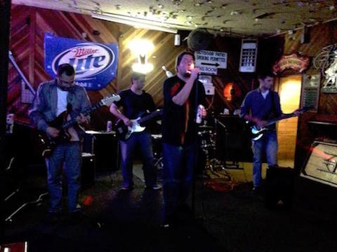 A band performing on stage in a dimly lit venue.