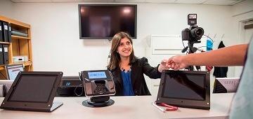 A person at an office desk pointing at a tablet screen.