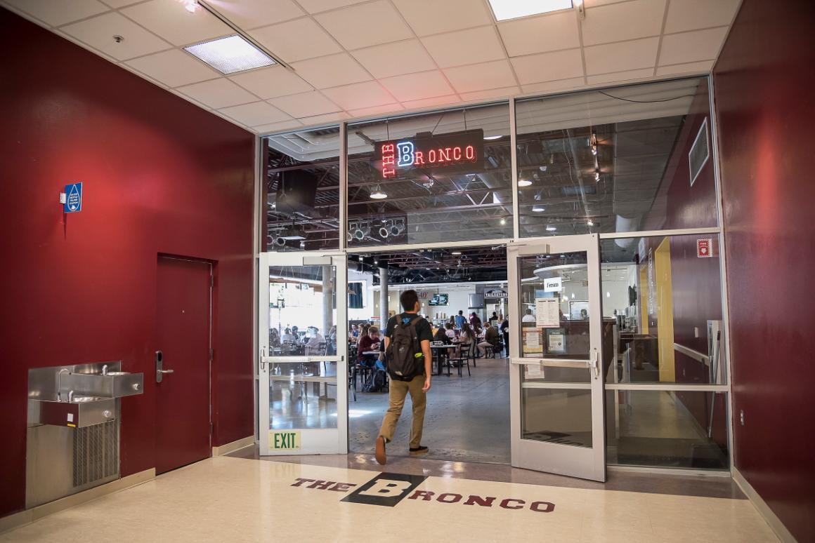 Person riding a bronco in a building lobby with glass doors.