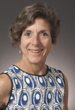 Alt text: Woman in blue and white patterned dress smiling, titled 'Angela Robbiano - HOF Committee'.