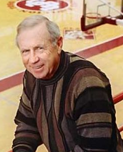 A man in a striped sweater standing in front of a basketball court.