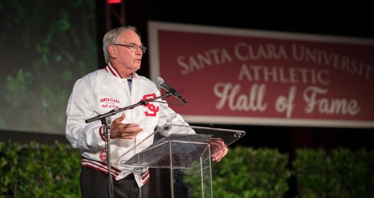 Man holding a plaque, standing next to a sign reading 