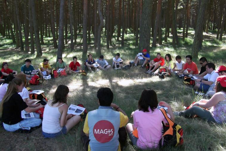People sitting on the ground in a forest, in a circle, for a retreat.