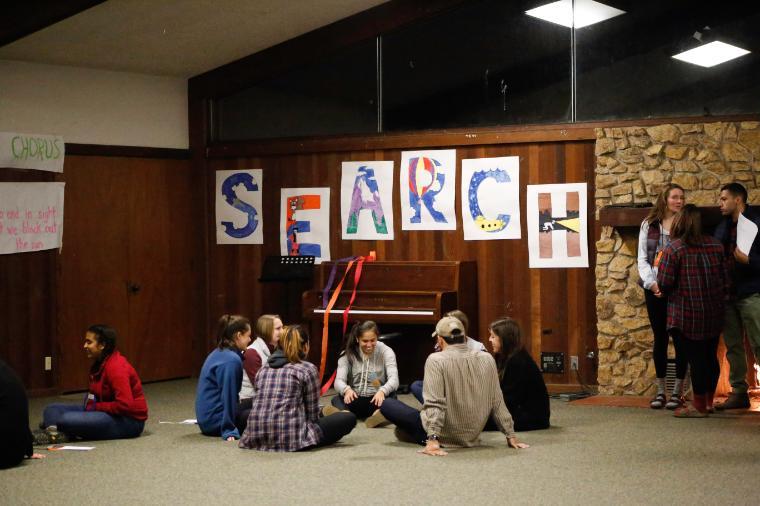 A group of people sitting on the floor with posters on the wall.