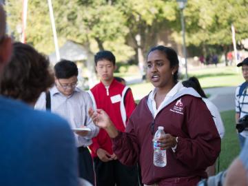 A group of people conversing outside on a sunny day.