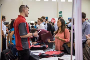 People interacting at a busy career fair booth.