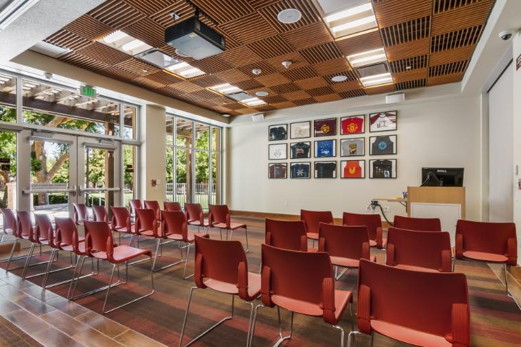 An open-air classroom with red chairs and a whiteboard. 