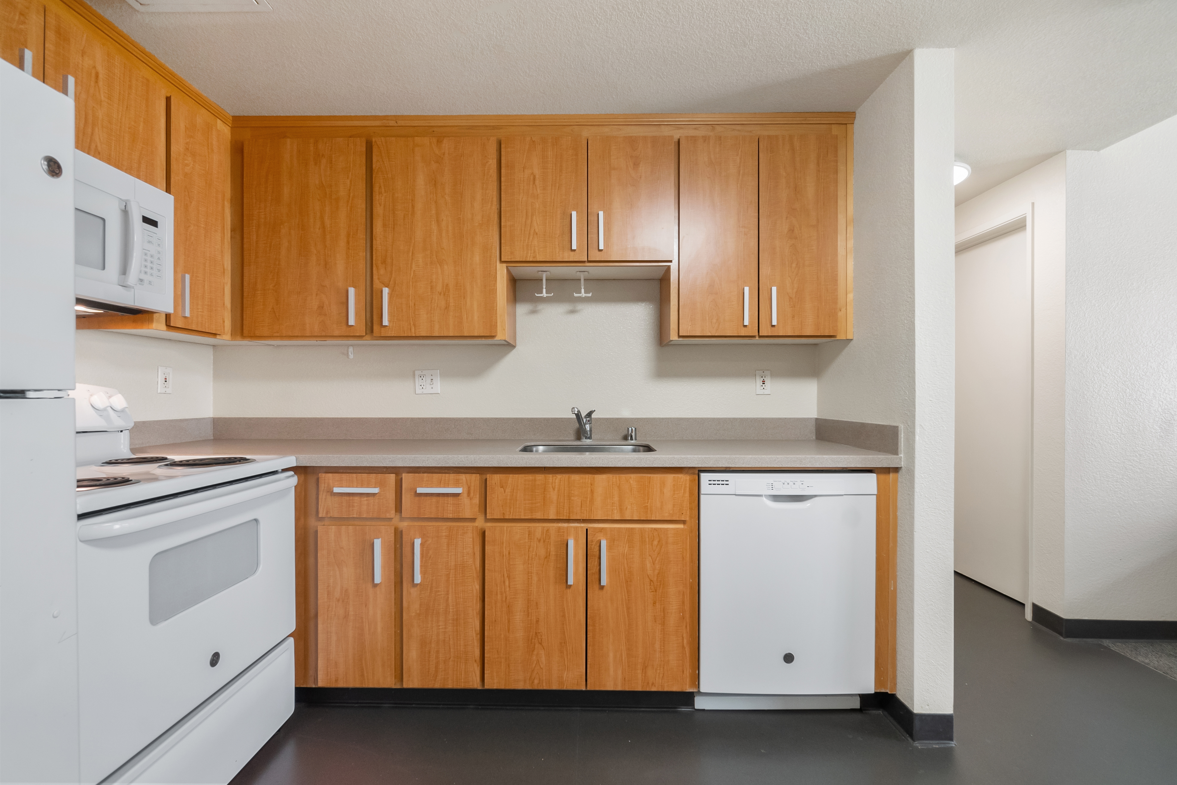 Modern kitchen with wooden cabinets, white appliances, and a gray countertop.