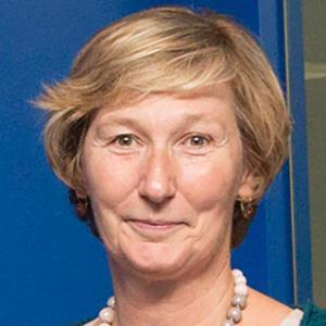 A person smiling in front of a blue background.