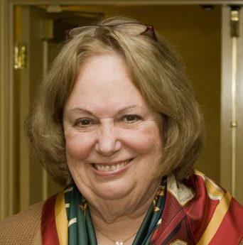 A woman smiling, wearing a colorful scarf.
