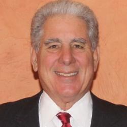 A person smiling in a suit and red tie.