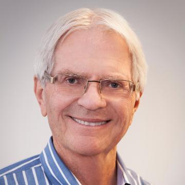 Man wearing glasses, smiling, in a striped shirt.