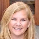 Alt text: Person smiling in front of a wooden background.