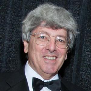 A man wearing a tuxedo and bowtie, smiling.