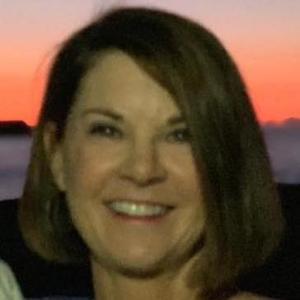 A woman smiling with a sunset background.