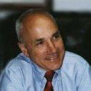 A smiling man wearing a blue shirt and red tie.