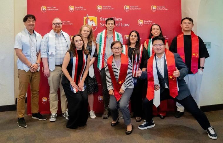 Decorative; students in graduation stoles smiling in front of a backdrop