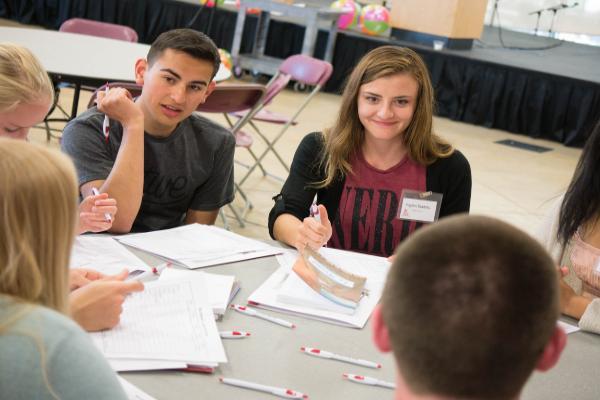 People sitting around a table, filling out forms.