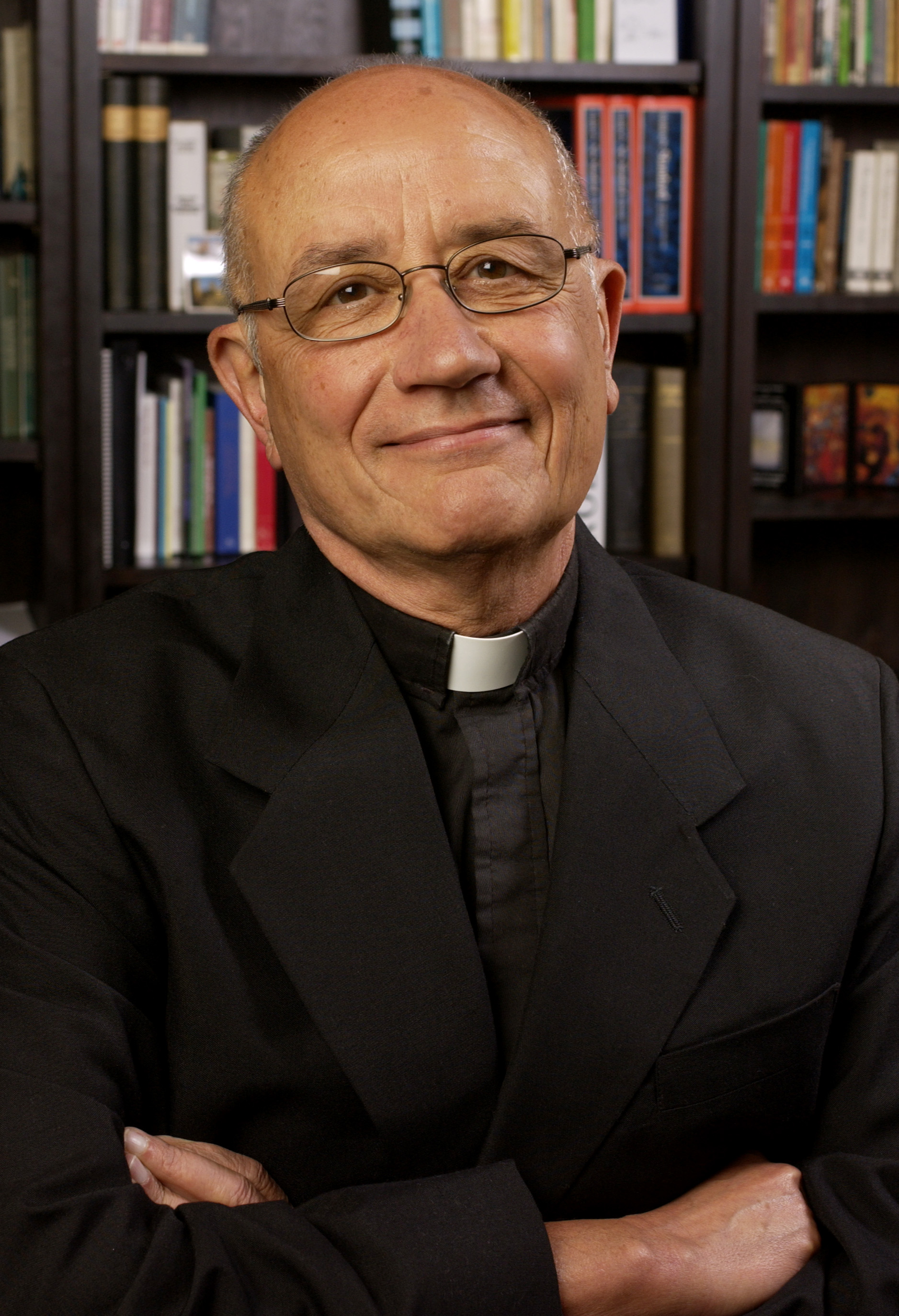 A person standing in front of a bookshelf, arms crossed. image link to story