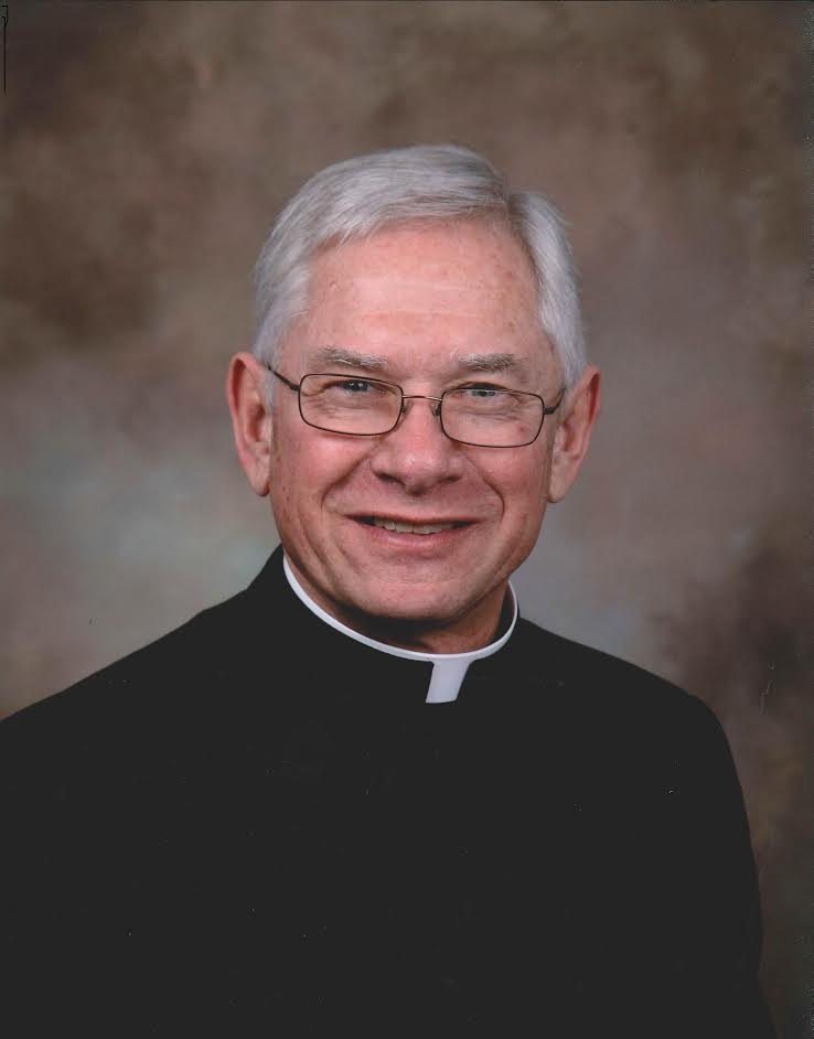 A person in clerical clothing smiling against a neutral background. image link to story