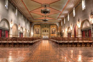 Interior of Santa Clara Mission with wooden pews and ornate decorations.