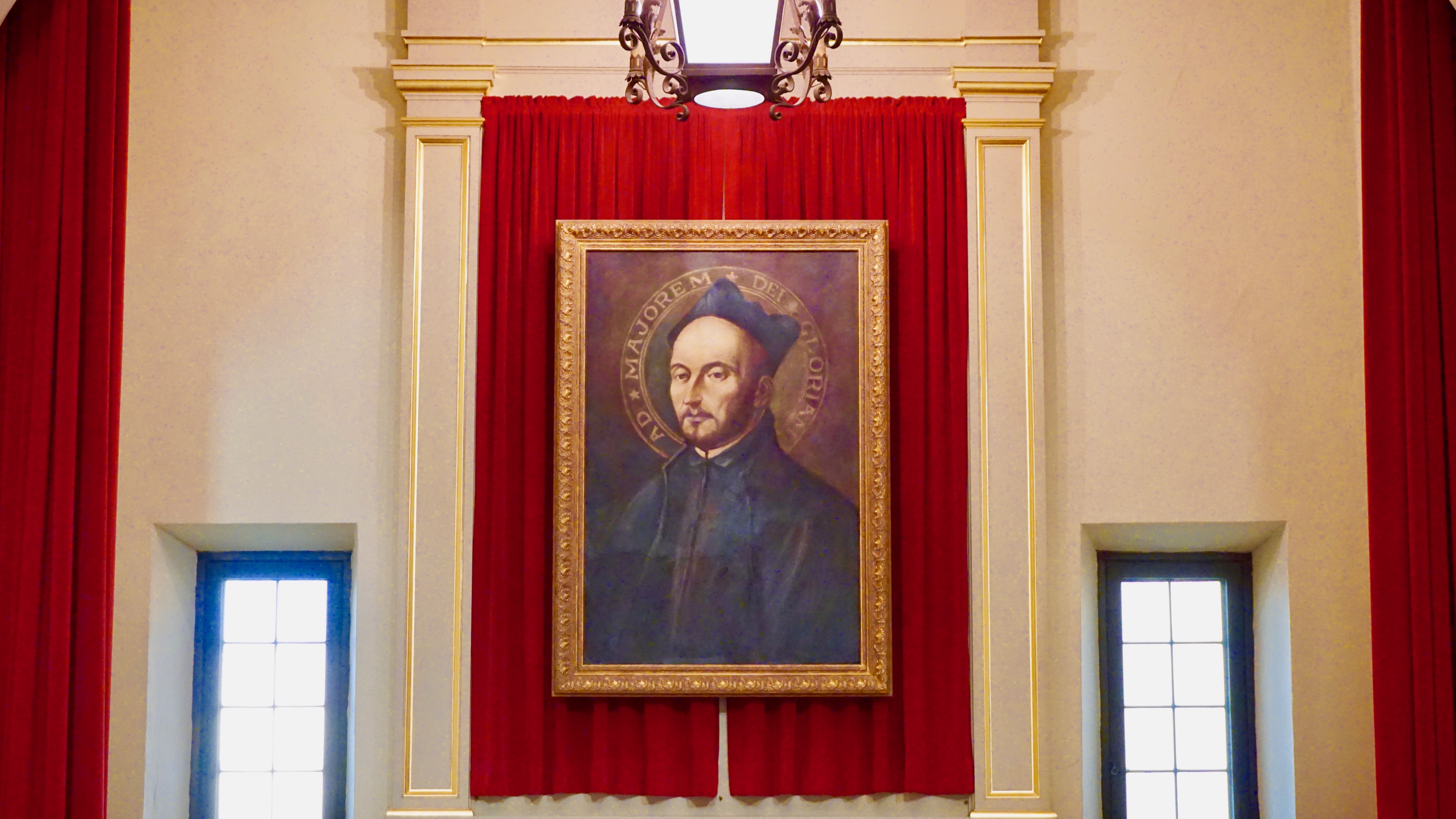 A framed painting of a person with a red background, titled 'St. Ignatius Painting'.