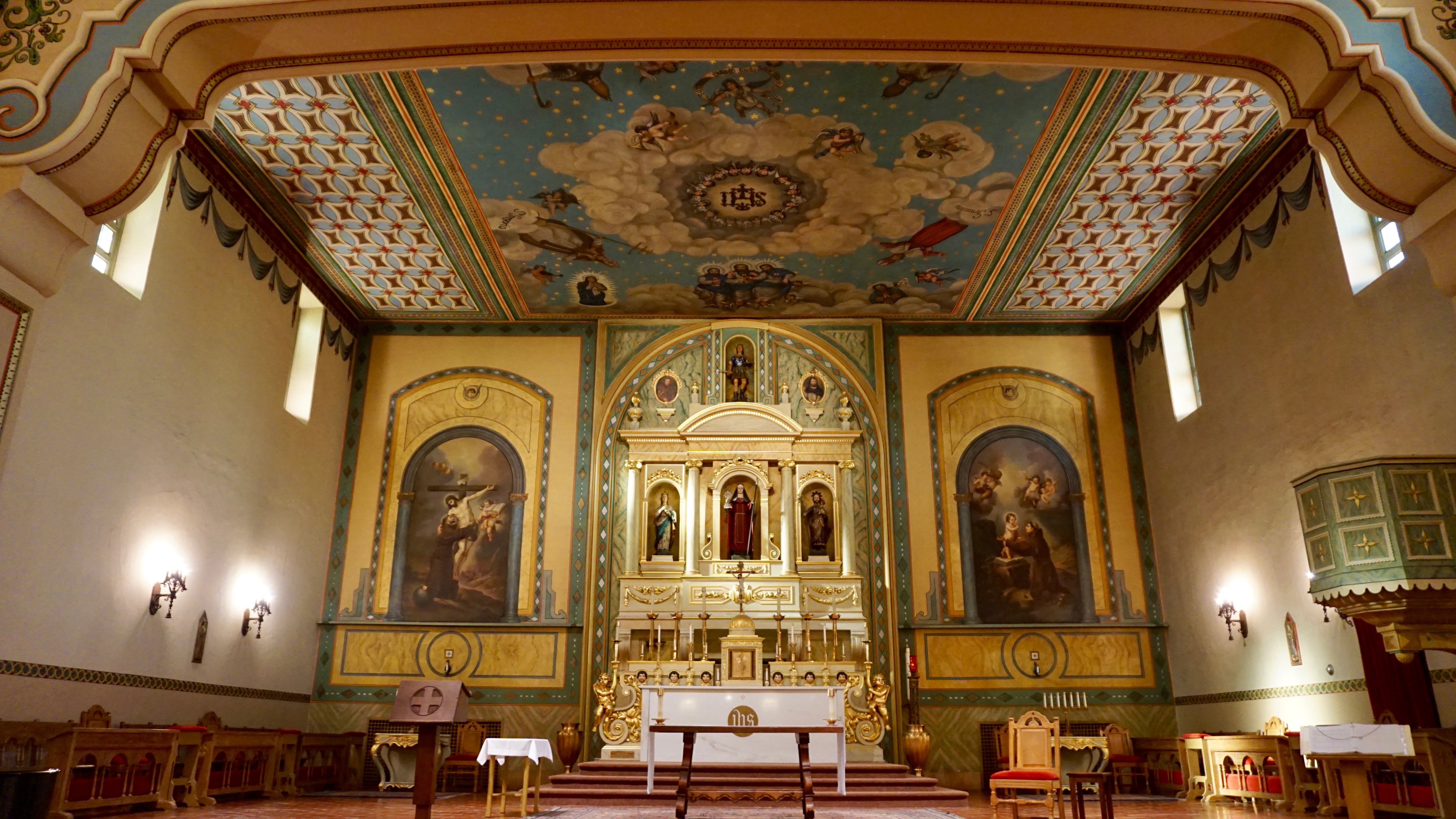 Ornate church sanctuary with paintings and a decorated ceiling titled 'Mission Sanctuary.'
