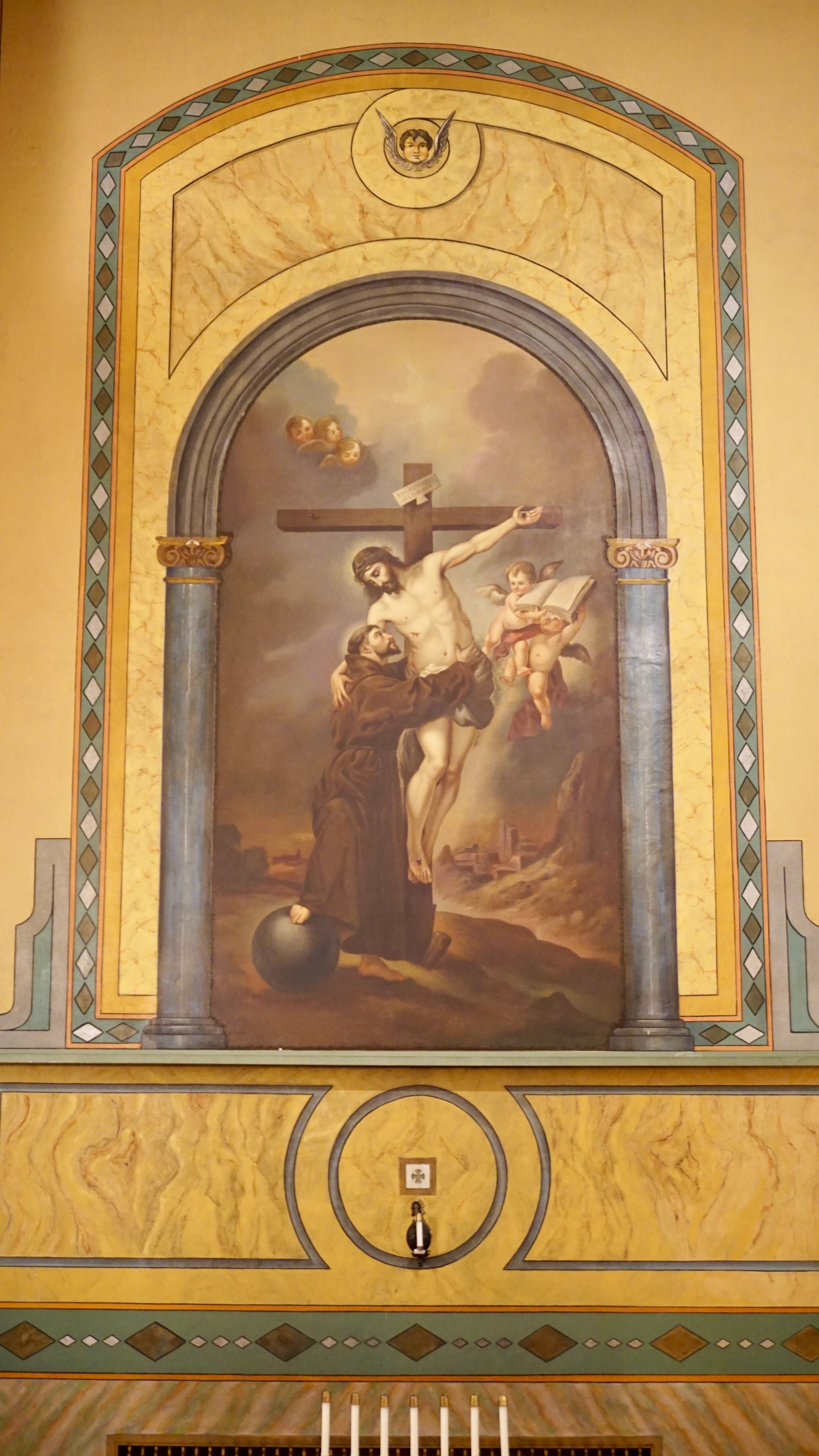 Painting of Saint Anthony holding child Jesus in an arched frame on the wall.
