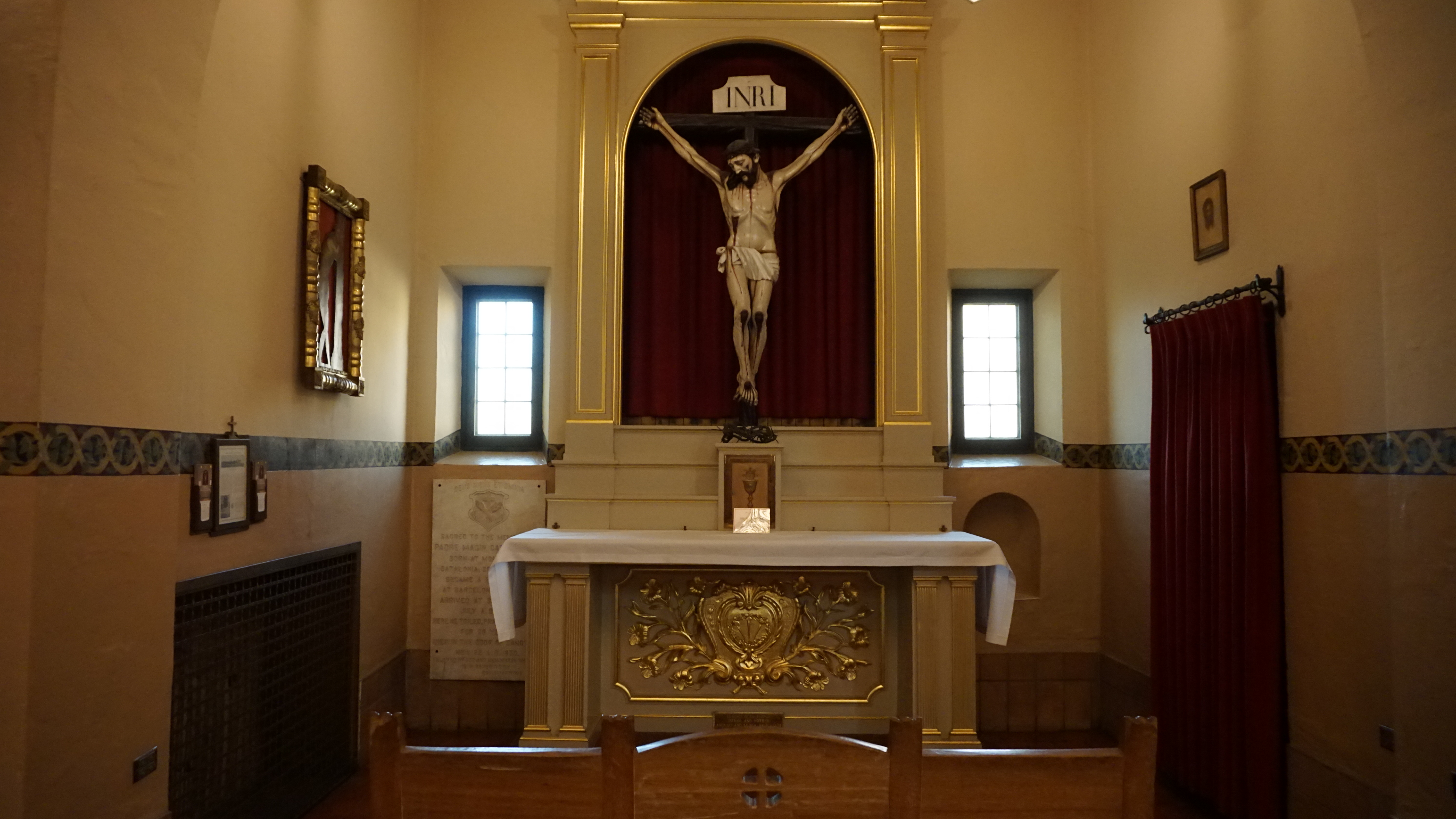 A crucifix hangs above an altar in a chapel.