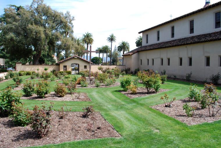 Alt text: Rose garden with cemetery overlook beside building.
