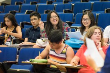 People sitting in a classroom, some smiling, some engaged in activities.