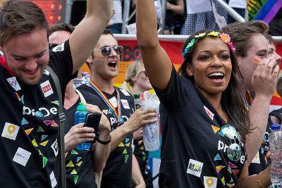 People celebrating in a crowd, some raising their hands and smiling with cameras.