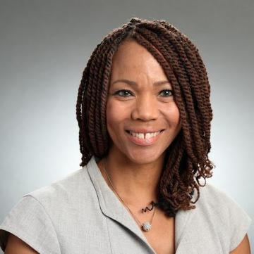 Smiling woman in business attire with a gray background. image link to story
