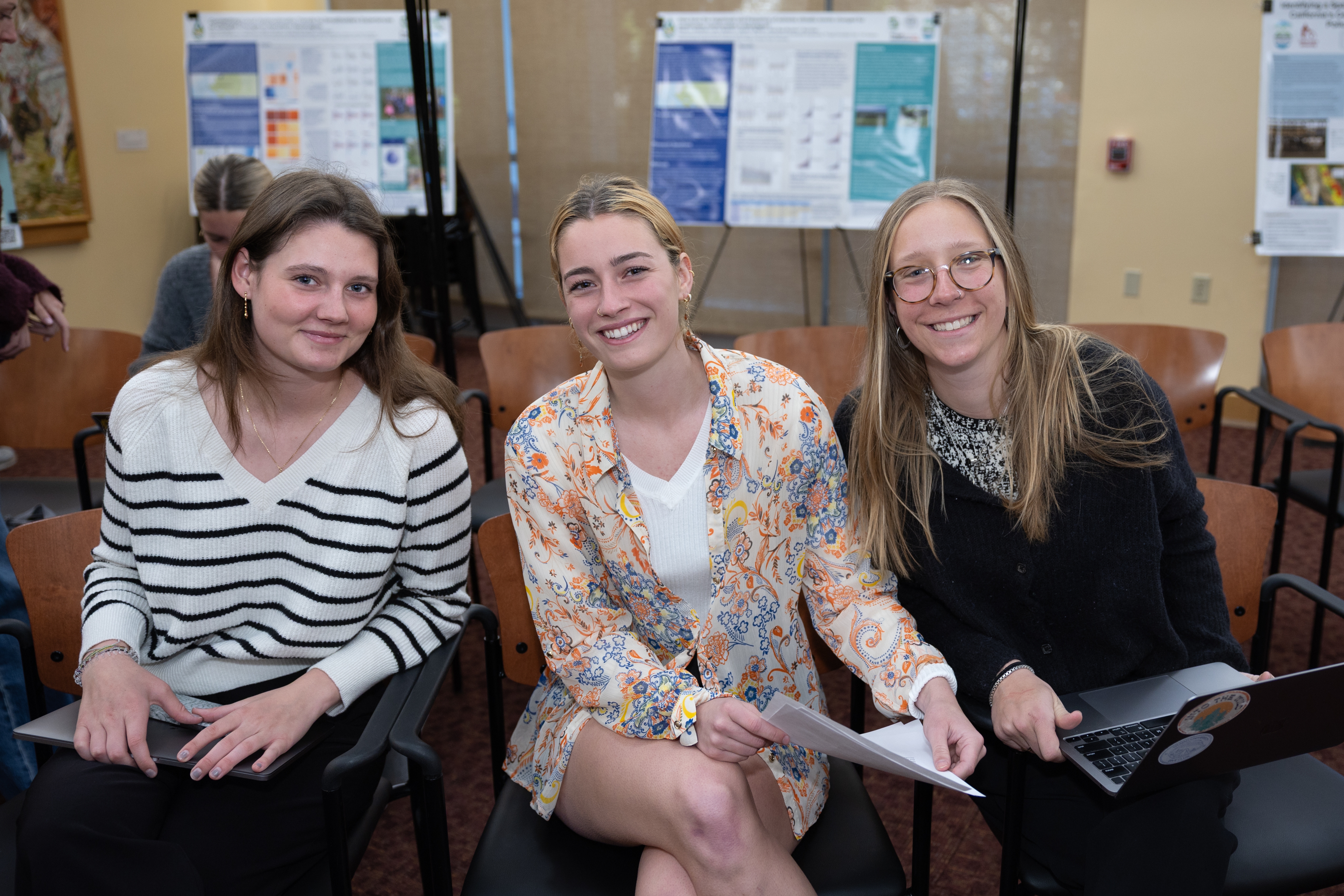 Three audience members smile during the 2025 Sustainability and EJ Symposium.