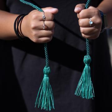 Two hands holding either end of the green sustainability minor graduation cord. Links to Sustainability minor page.
