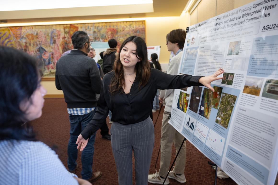 A student researcher speaking at a poster session image link to story