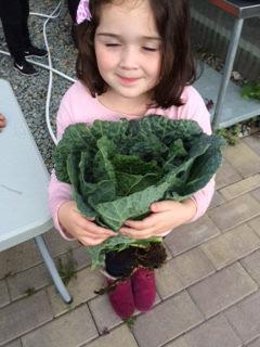 A child holding a large cabbage, smiling.