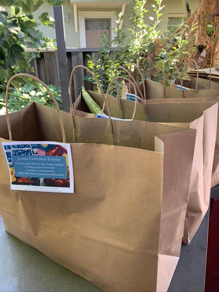 Three brown paper bags sit on a table next to a building.